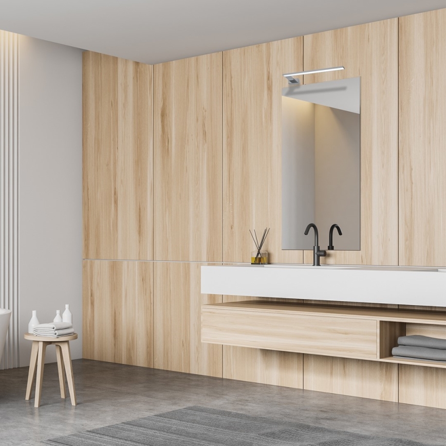 Drevená kúpeľňová skrinka s umývadlom a zrkadlom je umiestnená v kúpeľni s drevenými stenami. Na stolíku vedľa je uterák a kozmetika.