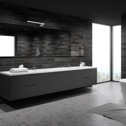 Dvojité umývadlo s tmavosivou skrinkou je umiestnené v modernej kúpeľni. Kúpeľňa má tmavé obklady zo stien a betónovú podlahu. Veľké okno poskytuje výhľad na krajinu.