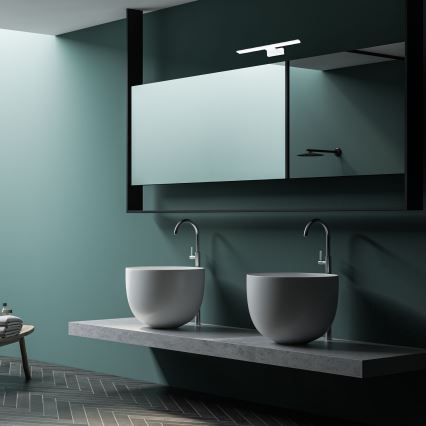 Dve umývadlá sú umiestnené na betónovom pulte pred zrkadlom v zelenej kúpeľni. Nad umývadlami sú vodovodné batérie. Na podlahe sú tmavé parkety.