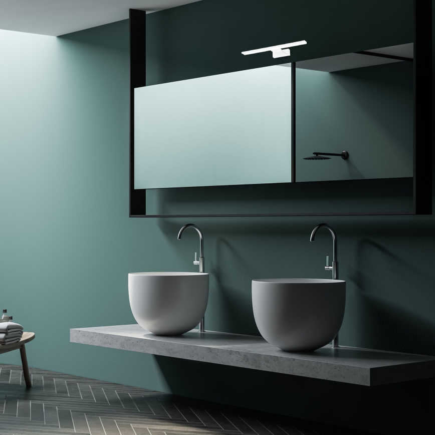 Dve umývadlá sú umiestnené na betónovom pulte pred zrkadlom v zelenej kúpeľni. Nad umývadlami sú vodovodné batérie. Na podlahe sú tmavé parkety.