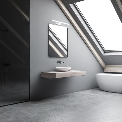 Umývadlo je umiestnené na drevenom pulte pod zrkadlom v sivej podkrovnej kúpeľni s oknom v streche a sprchovacím kútom.