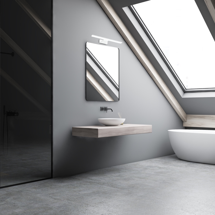 Umývadlo je umiestnené na drevenom pulte pod zrkadlom v sivej podkrovnej kúpeľni s oknom v streche a sprchovacím kútom.