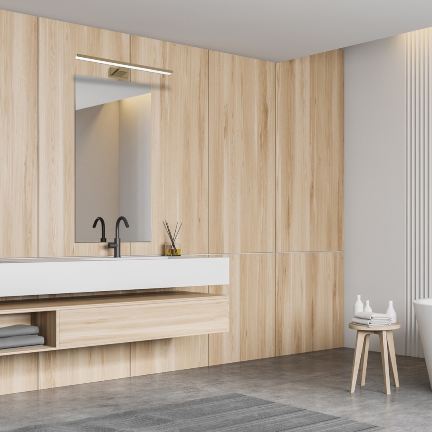 Drevená umývadlová skrinka s dvoma zásuvkami je umiestnená v kúpeľni s obkladmi z bielych dlaždíc. Nad skrinkou je okrúhle zrkadlo a nástenné svietidlo. V blízkosti je drevený stolík s uterákmi a kozmetikou.