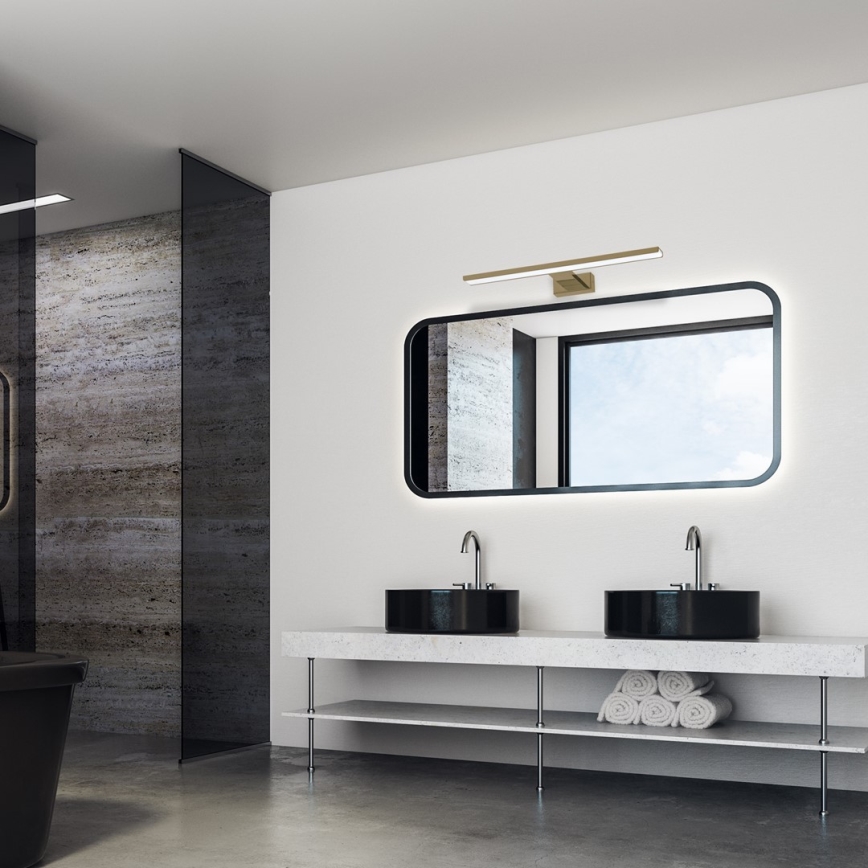 Drez s batériou je umiestnený na drevenom nábytku v kúpeľni. Zrkadlo s osvetlením visí nad drezom. Steny sú obložené svetlým drevom.