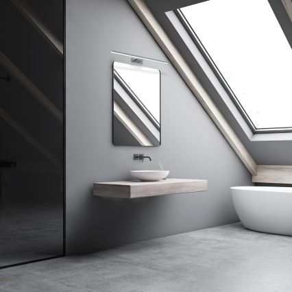 Umývadlo sa nachádza na drevenom pulte v sivej kúpeľni pod štvorcovým zrkadlom. Kúpeľňa má šikmú strechu so strešným oknom a betónovú podlahu. V kúpeľni je vidieť aj voľne stojacu vaňu.