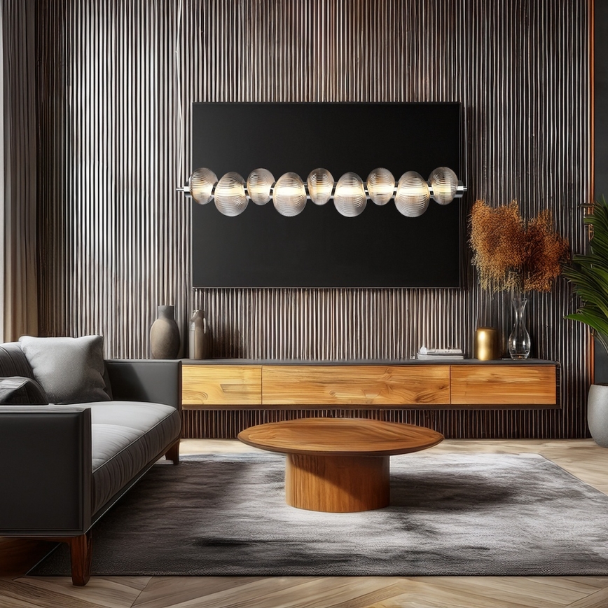 Svietidlo s guľôčkami je pripevnené nad televízorom. Nachádza sa v modernej obývacej izbe s dreveným nábytkom a koženou sedačkou.