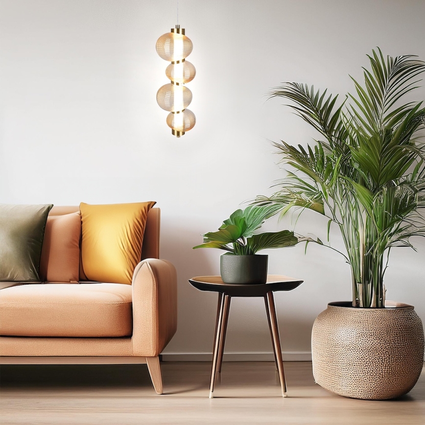 Svietidlo visí v obývacej izbe. Skladá sa zo štyroch prepletaných sklenených guľôčok. Nachádza sa nad hnedou sedačkou s vankúšmi a vedľa konferenčného stolíka s kvetináčmi a veľkou palmami v kvetináči.
