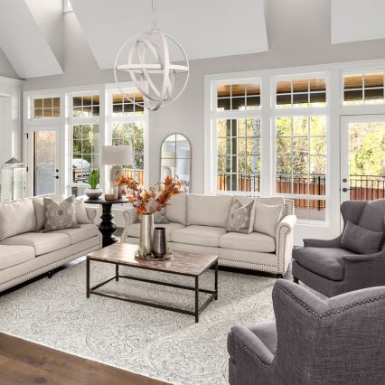 Svetlozelená pohovka s vankúšmi sa nachádza v tmavosivej miestnosti. Nad pohovkou visí moderné biele závesné svietidlo v tvare gule. Miestnosť má veľké okná a svetlý drevený podlaha.