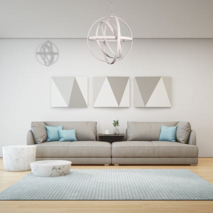 Svietidlo visí v obývačke. Je to guľové svietidlo s prepletenými kruhmi. Nachádza sa nad sedačkou pred tmavou stenou s mramorovým vzorom a drevenými panelmi po stranách.