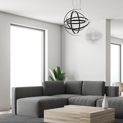 Svietidlo v tvare gule s prepletenými kruhmi visí v spálni. Nad posteľou s tmavosivou prikrývkou je svetlozelená stena. Drevená podlaha dopĺňa interiér.