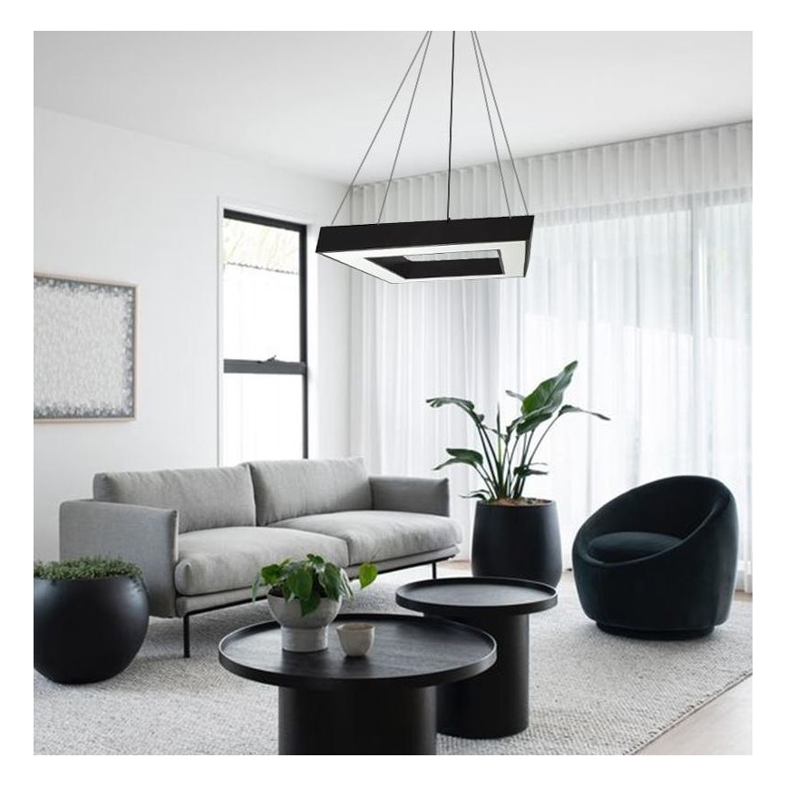 Štvorcové závesné svietidlo svieti v obývacej izbe. Izba obsahuje sivú sedačku, dva nízke stolíky, kreslo a rastliny v kvetináčoch.
