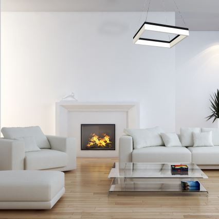 Svetlo svieti nad svetlou sedačkou v miestnosti s tmavosivou stenou a bielou podlahou. Nízky kovový stolík stojí pred sedačkou a vedľa je betónový odkladací stolík. V pozadí je biele záves.