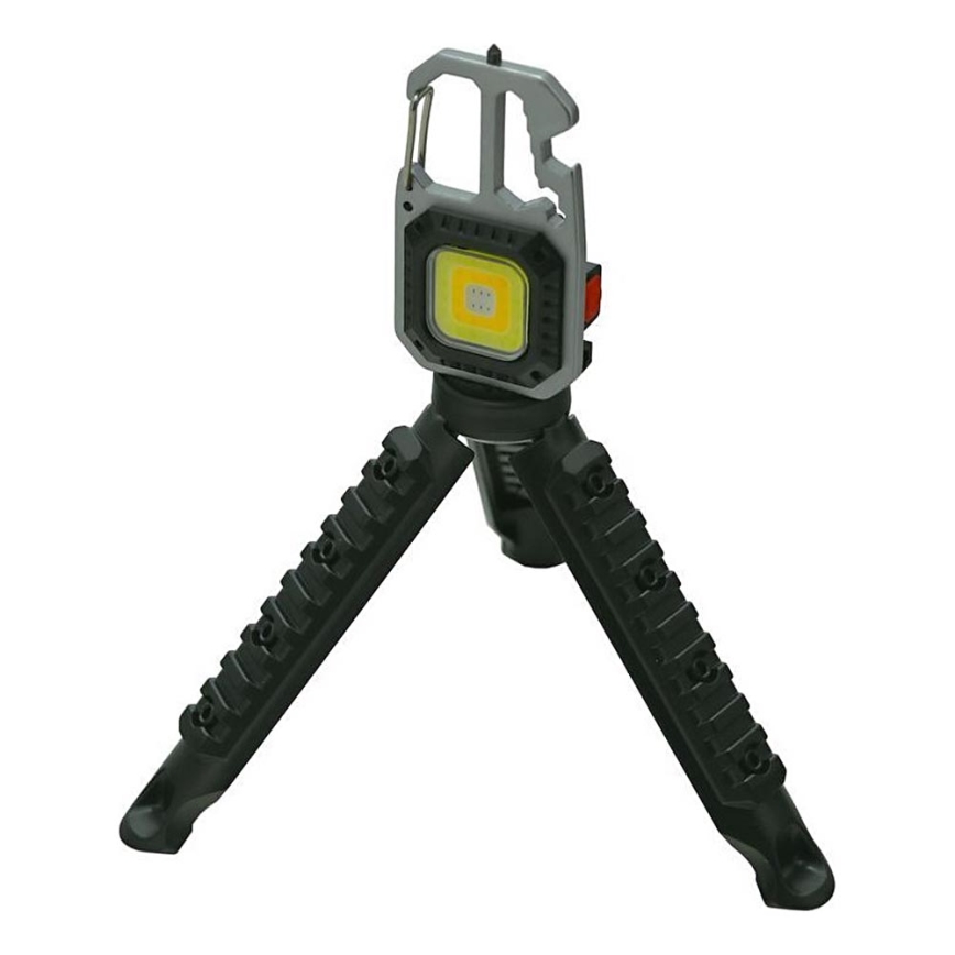LED svetlo s karabínou a otváračom na vrchu, umiestnené na trojnožke s drážkami. Svetlo svieti na bielu farbu. Svetlo je umiestnené na bielom pozadí.