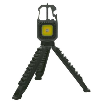 Prenositelná LED lampa s trojnožkou svieti. Lampa je tmavosivá, má karabínu a integrovaný otvárač. Stojan je z plastického materiálu s drážkami.