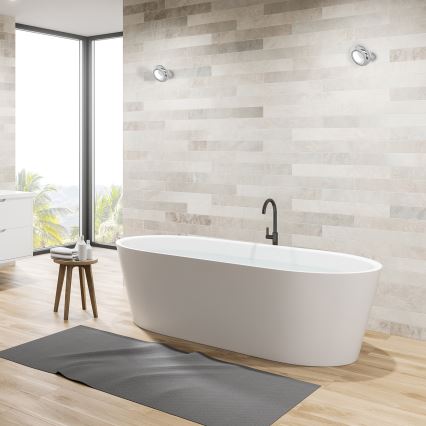 Biela voľne stojaca vaňa s vodou sa nachádza v kúpeľni s dlaždicovou stenou a drevenou podlahou. Pred vaňou je tmavá rohož. V blízkosti je malý drevený stolík.