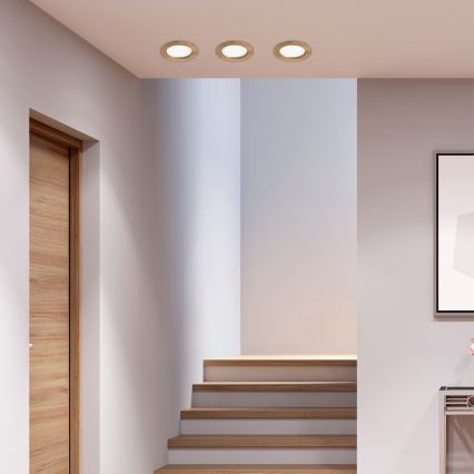 Tri okrúhle svietidlá sú osvetlené na strope. Nachádzajú sa v chodbe s drevenými schodmi a dverami.