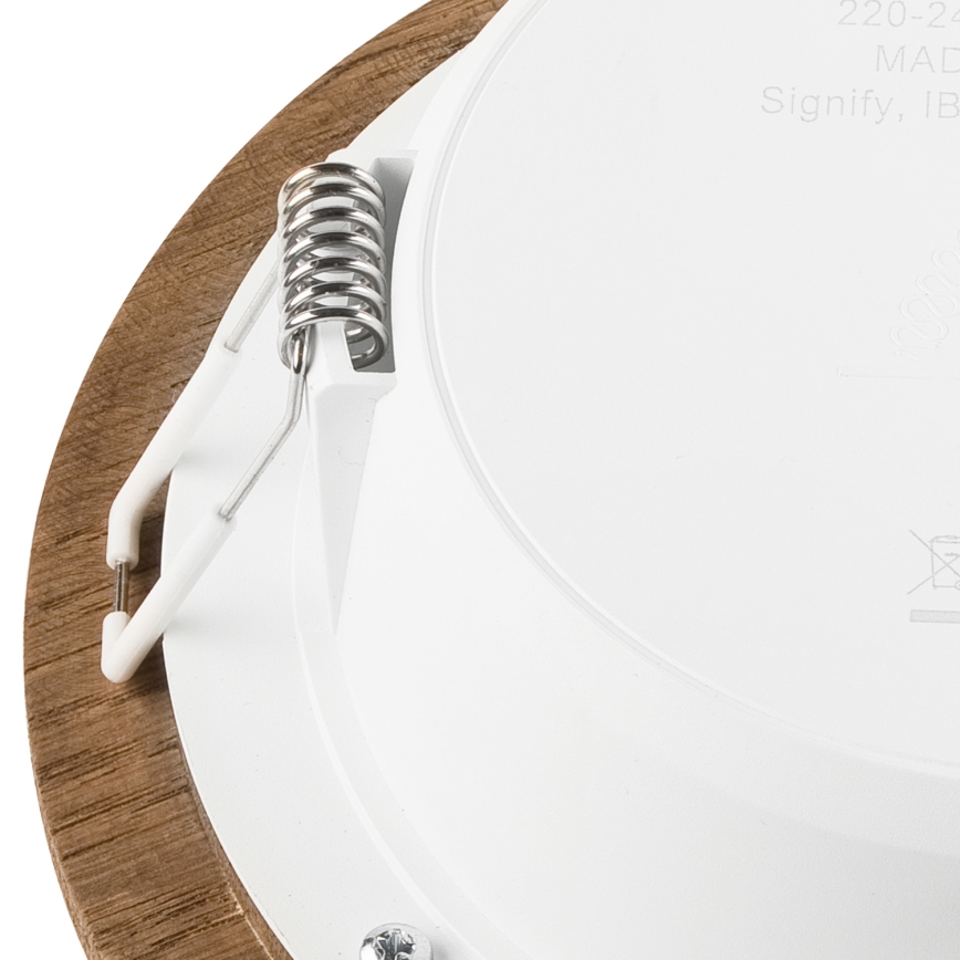 Svietidlo s dreveným rámom a bielym vnútorným telom sa upevňuje pomocou pružiny a plastových háčikov. Vidno časť označenia: „220-240V, MADE IN CHINA, Signify, IP20“.