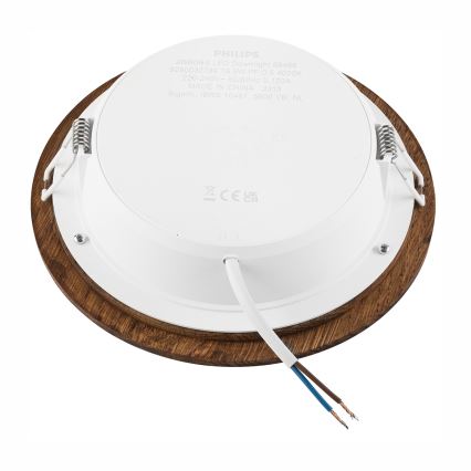 Svietidlo s dreveným rámom je pripojené k elektrickému vedeniu. Zadná strana svietidla ukazuje technické údaje: 286065 LED Downlight 59-468, 9290032789 16 5W PF:0.5 4000K, 220-240V-50/60Hz 0.120A, MADE IN CHINA 2313, Signify IBRS 10461, 5600 VB, NL.