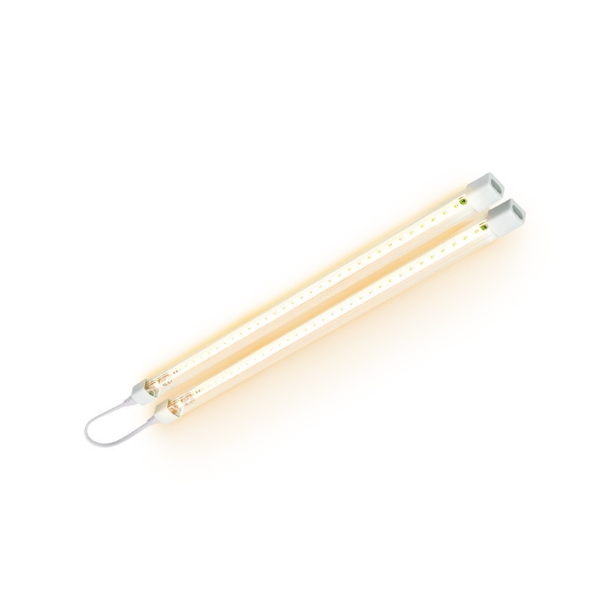Dve LED trubice svietia na bielom pozadí. Sú spojené káblom a umiestnené diagonálne. Trubice sú dlhé a úzke, s viditeľnými LED diódami.