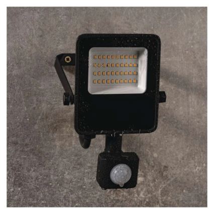 LED svetlo s detektorom pohybu je pripevnené k stene. Svetlo je čierne, štvorcového tvaru a obsahuje mnoho malých LED diód. Detektor pohybu je umiestnený pod svetlom. Celá zostava je mierne mokrá.
