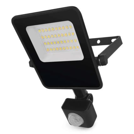 LED svetlo s pohybovým senzorom svieti. Má štvorcový tvar, čiernu farbu a je upevnené na kovovom držiaku. Svetlo je osadené mnohými malými LED diódami. Pozadí je biele.