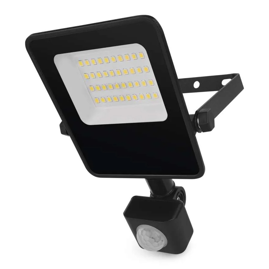 LED svetlo s pohybovým senzorom svieti. Má štvorcový tvar, čiernu farbu a je upevnené na kovovom držiaku. Svetlo je osadené mnohými malými LED diódami. Pozadí je biele.