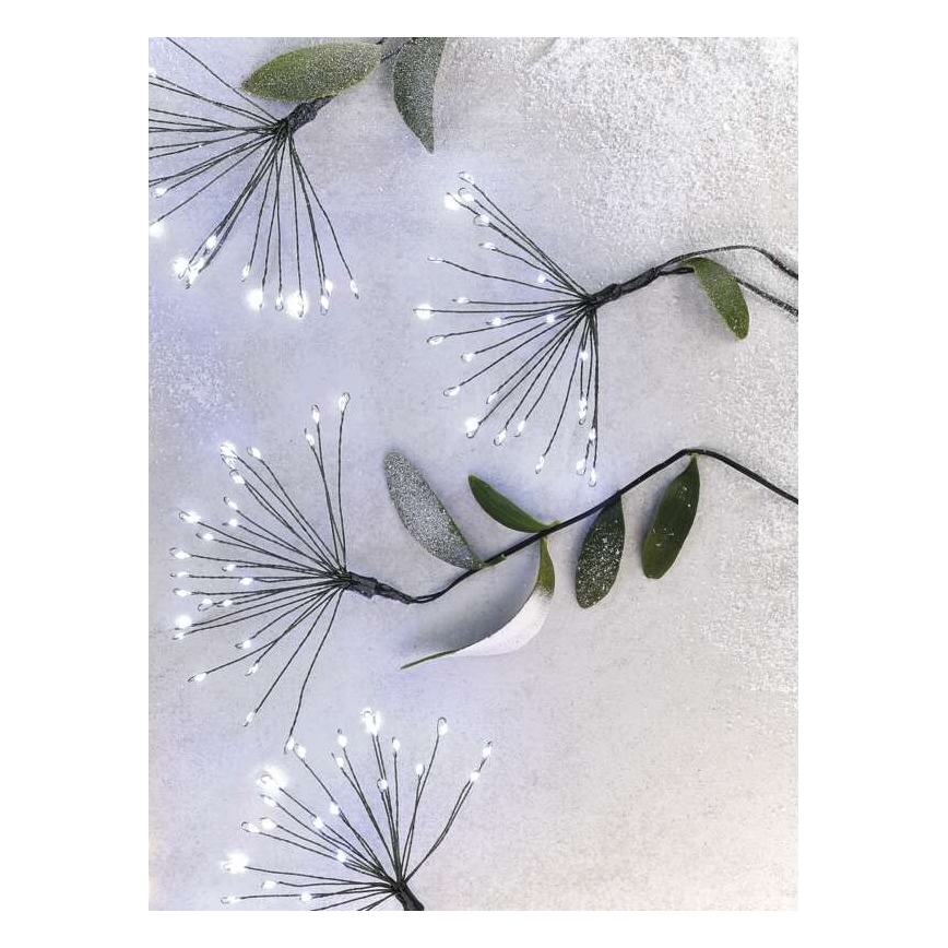 Svetlíkové vetvičky s bielymi LED diódami sú umiestnené na svetlom sivom pozadí. Vetvičky sú pripevnené k tenkému čiernemu drôtu a zdobia ich umelé listy.