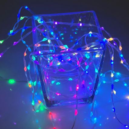 Svetelný reťaz s farebnými LED diódami je umiestnený v sklenenom štvorcovom váze. Reťaz je prevlečený cez vázu a voľne sa rozkladá okolo nej na svetlom povrchu. Svetlo z diód má rôzne farby - modrú, ružovú, zelenú a červenú.