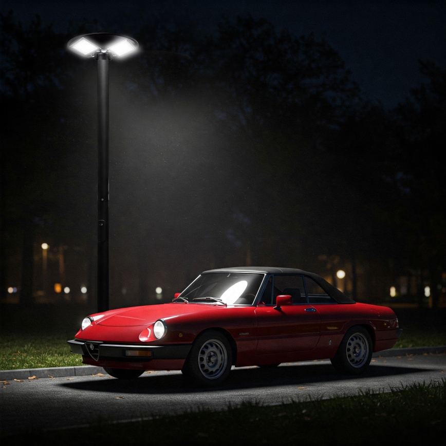 Červené Alfa Romeo Spider stojí zaparkované pri nočnom osvetlení na chodníku. V pozadí sa nachádzajú stromy a slabo viditeľné pouličné lampy.