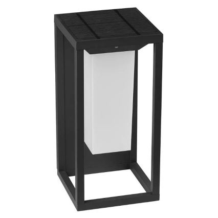 Solárny vonkajší svietiaci stĺpik, ktorý svieti, je umiestnený na exteriéri. Má čierny kovový rám a biely svetelný zdroj. Solárny panel je na vrchu.
