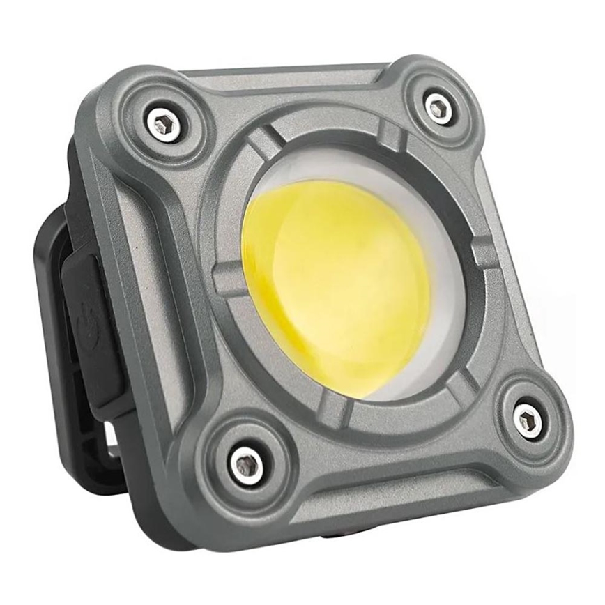 Štvorcová LED svietidlo svieti. Je sivé, kovové, s viditeľnými skrutkami a bočným vypínačom. Svietidlo je izolované od pozadia.