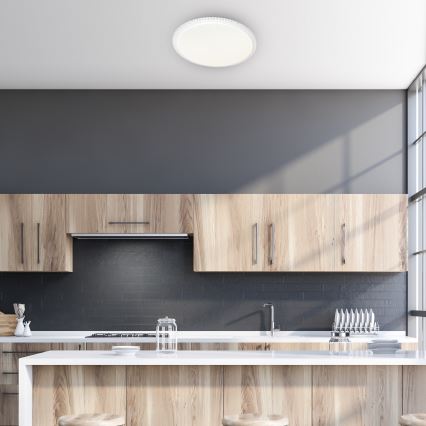 Svietidlo je pripevnené na strope. Svieti v modernej kuchyni s drevenými skrinkami a tmavou dlažbou. Kuchynská linka je vybavená ostrovčekom.