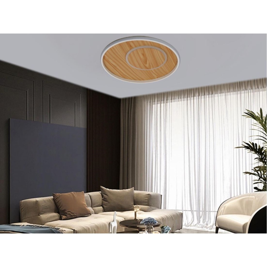 Svietidlo je pripevnené k stropu. Má okrúhly tvar, drevenú vložku a biely okraj. Nachádza sa v obývacej izbe s pohovkou, konferenčným stolíkom a závesmi.