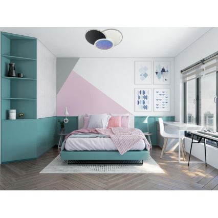 Dvojdielna stropná lampa svieti v spálni. Lampa je umiestnená na strope nad posteľou s ružovou prikrývkou a svetloružovými vankúšmi. Spálňa má bledoružové a tyrkysové steny, drevenú podlahu a pracovný stôl.