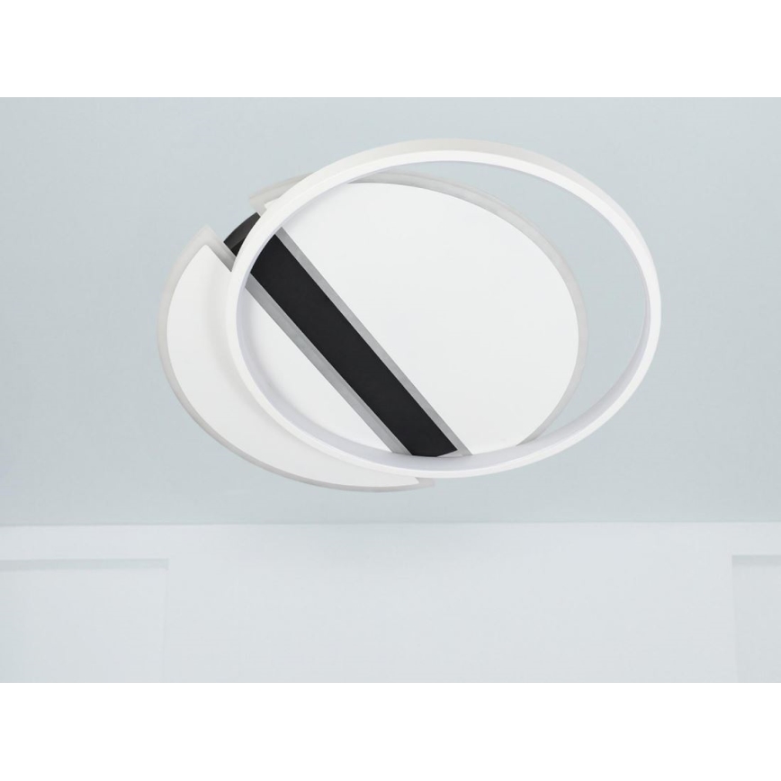 Svietidlo je pripevnené na svetlom strope. Skladá sa z dvoch prekrývajúcich sa bielych kruhov a jedného čierneho pásu medzi nimi. Svietidlo je umiestnené v svetlej miestnosti.