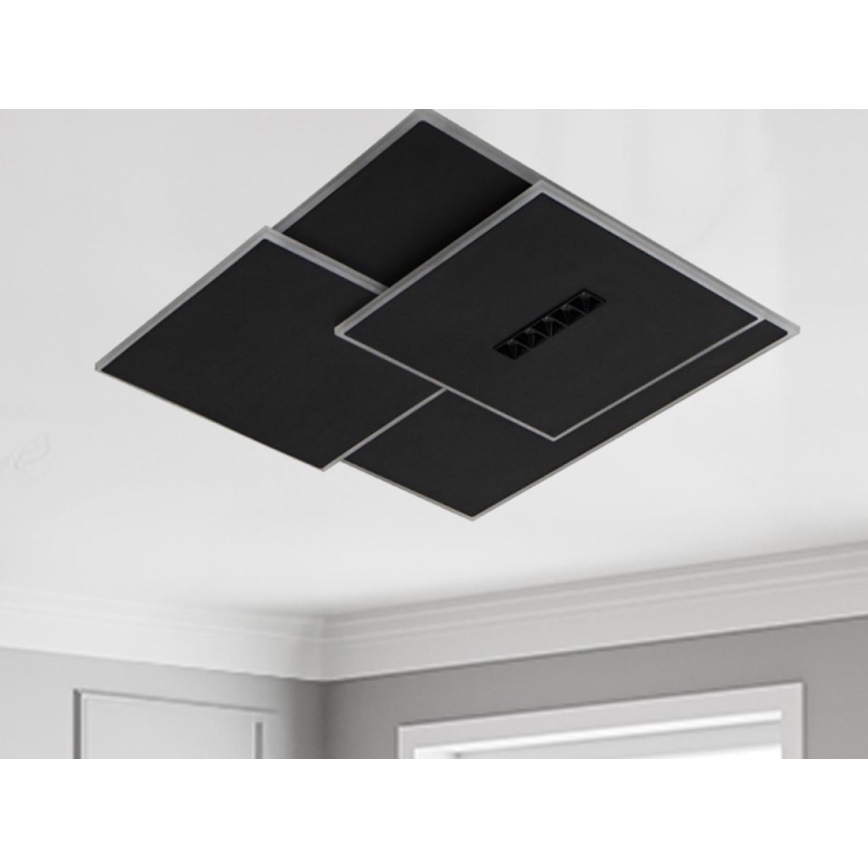 Čierne štvorcové svietidlo s integrovanými svetlami je pripevnené k stropu. Svietidlo je zložené z prekrývajúcich sa panelov s tenkým strieborným rámom. Je umiestnené v interiéri miestnosti s bielym stropom a svetlosivými stenami.
