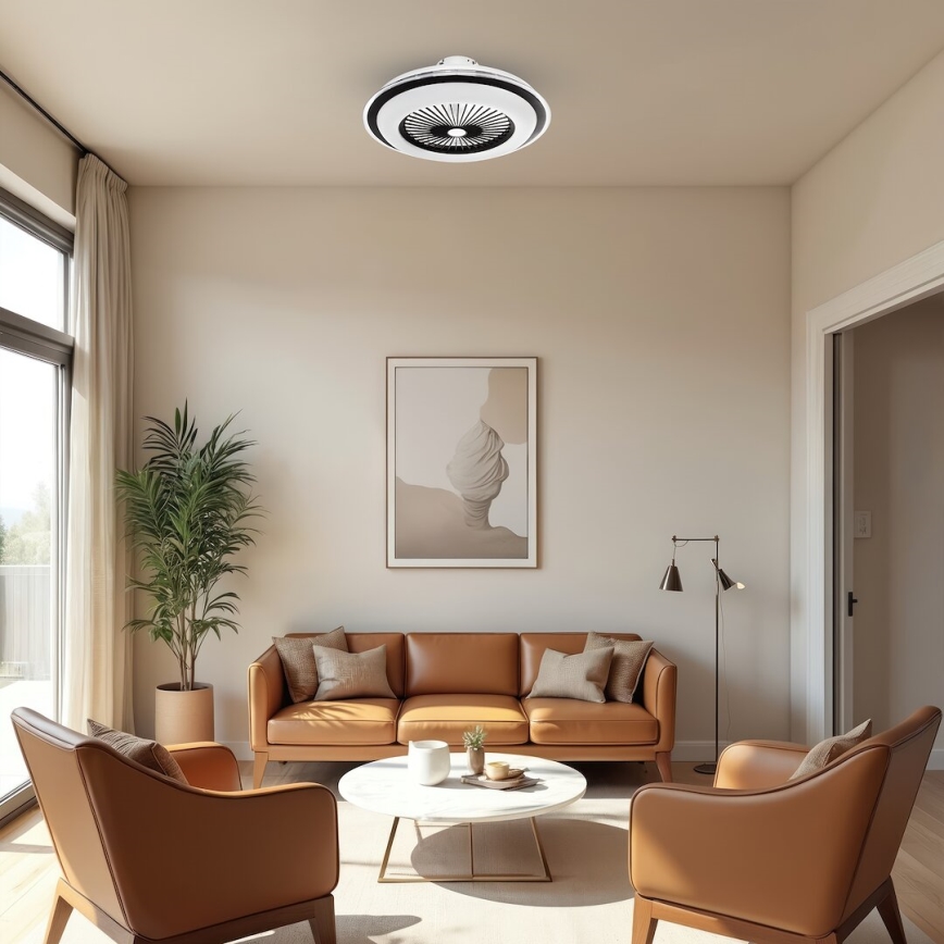 Stropný ventilátor s integrovaným osvetlením je umiestnený v obývacej izbe. Ventilátor je nehybný. Izba je zariadená hnedou koženou sedačkou, dvoma kreslami a konferenčným stolíkom. V pozadí je obraz a vysoká rastlina.