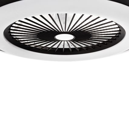 Stropný ventilátor s čiernymi lopatkami a bielym krytom je pripevnený k stropu. Ventilátor je v pokoji. Biele pozadie.