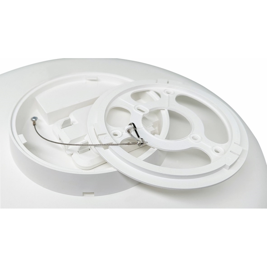 Biela plastová základňa detektora je čiastočne rozobratá. Odnímateľný kruhový prvok je oddelený od hlavnej základne, pričom je viditeľné tenké kovové lanko. Súčasťou je aj priestor pre zapojenie kábla.