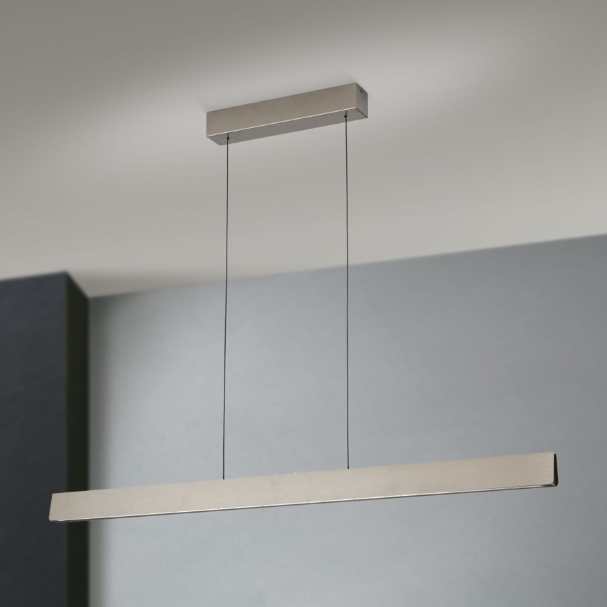 Dlhá, obdĺžniková kovová lampa visí zo stropu na dvoch kábloch. Lampa je pripevnená k štvorcovému stropnému držiaku. Pozadie tvorí svetlosivá stena.