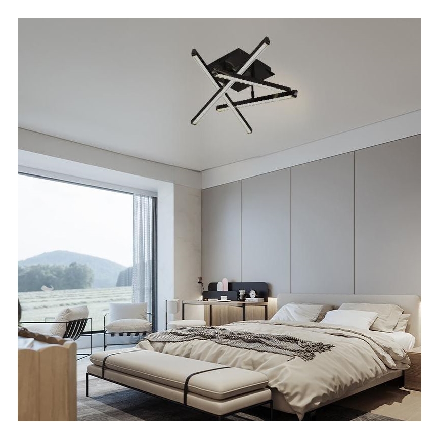 Moderné stropné svietidlo s prekríženými ramenami svieti v spálni. Svietidlo je umiestnené na strope nad posteľou s čelom. Spálňa má veľké okno s výhľadom do krajiny.