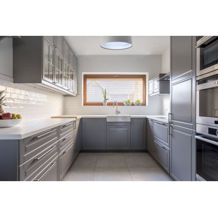 Šedá kuchynská linka s dreveným oknom a vstavanými spotrebičmi. Uprostred je umiestnená kuchynská pracovná doska s drezom. Na strope visí stropné svietidlo.