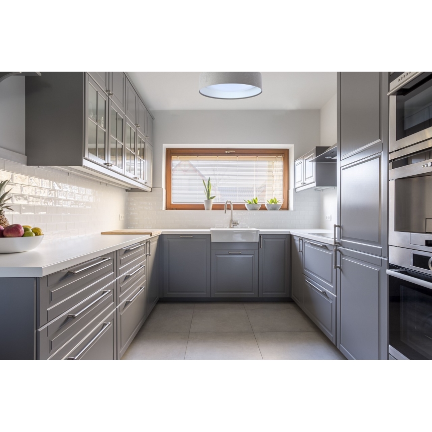 Šedá kuchynská linka s dreveným oknom a vstavanými spotrebičmi. Uprostred je umiestnená kuchynská pracovná doska s drezom. Na strope visí stropné svietidlo.