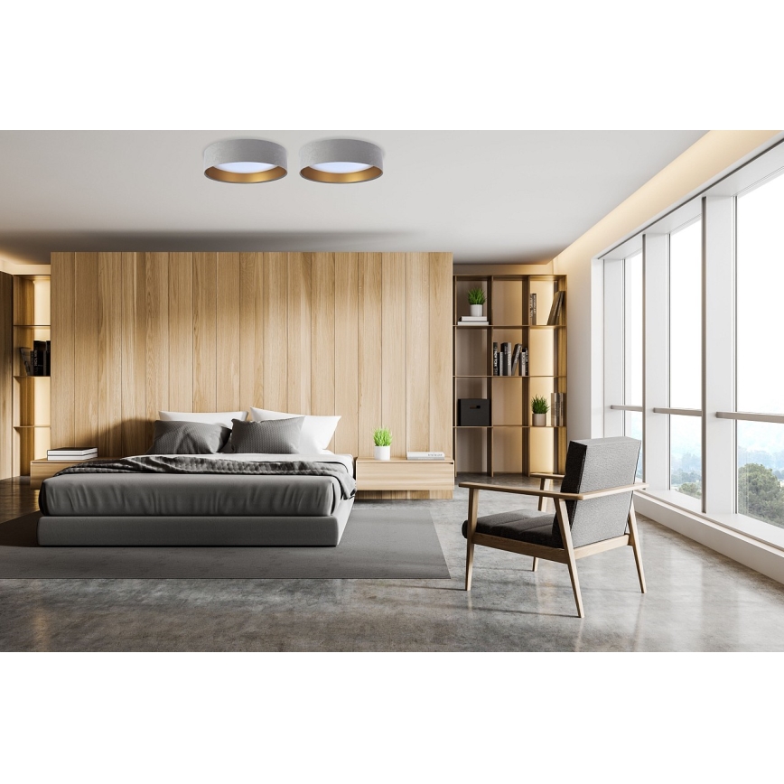 Dve stropné svietidlá s bielym tienidlom a zlatým lemom sú osadené na strope. Nachádzajú sa v spálni s drevenou stenou, posteľou a kreslom.