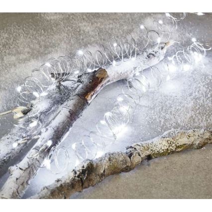 Svetelný reťaz s bielymi LED diódami je stočený na dvoch bielych konároch. Konáre ležia na snehobielom povrchu.