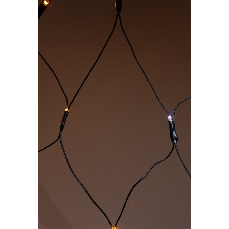 Sieť svetielok s teplými a studenými bielymi LED diódami, pripevnenými na čiernych kábloch, vytvárajúcich diamantový vzor, je zobrazená pred hnedým pozadím.