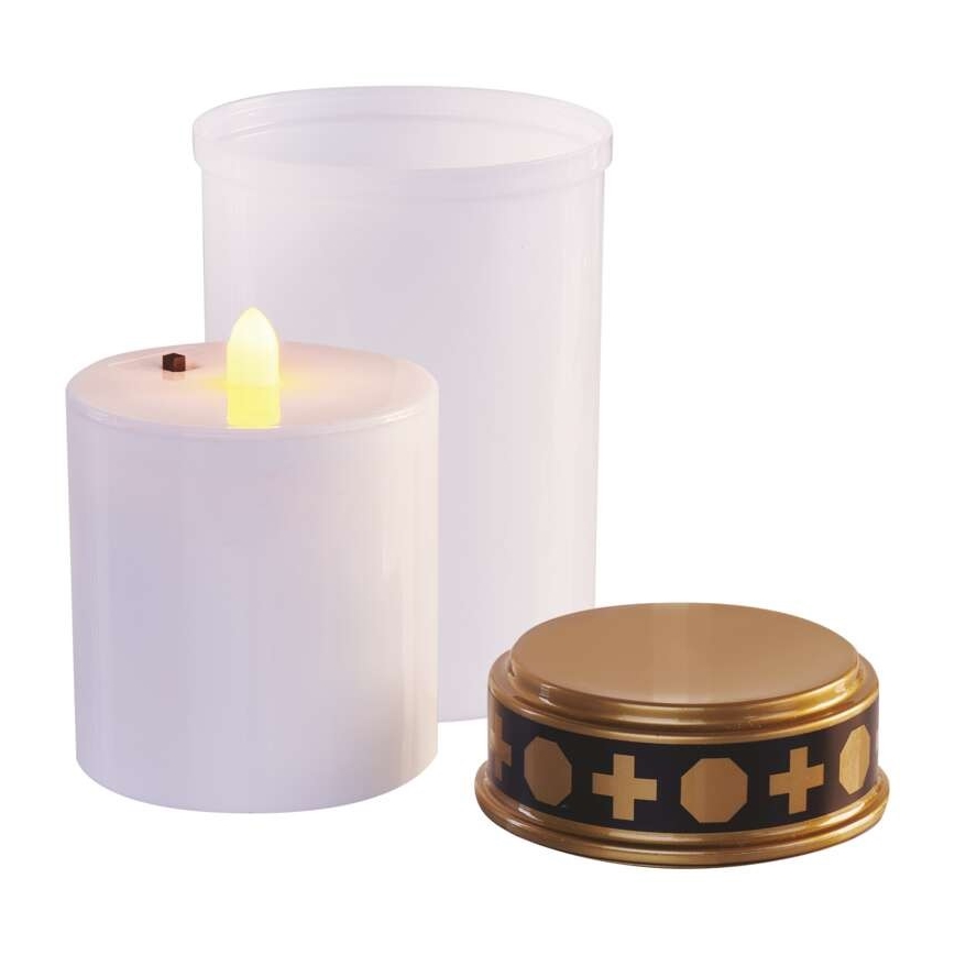 Elektrická sviečka svieti. Je súčasťou sady s bielym ochranným puzdrom a zlatým podstavcom s čiernym dekoratívnym pásom obsahujúcim kríže a geometrické tvary.