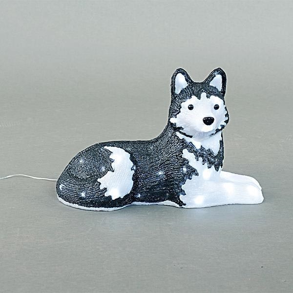 Svietíca so psom plemena sibírsky husky leží na svetlošedej ploche. Svietíca je prevažne čierna a biela, s bielymi detailmi a integrovanými LED diódami. Tenký kábel je viditeľný zo zadnej strany.