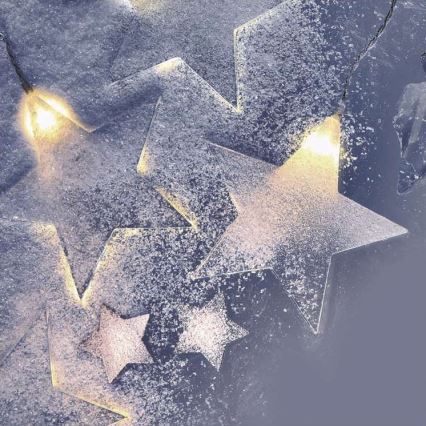 Hviezdne svetielka svietia. Sneh pokrýva hviezdy. Svetlá sú teplej bielej farby.