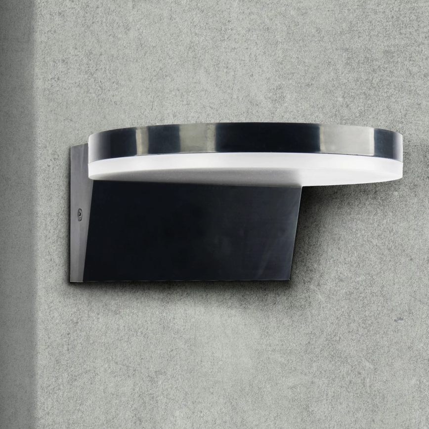 Nástené svietidlo s oválnym tienidlom je pripevnené k betónovej stene. Svietidlo je tmavosivé s lesklým povrchom. Svetlo vyžaruje z kruhového, bieleho difúzora v oválnej časti tienidla.